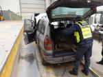 funkcjonariusz łotewskiego cła z psem służbowym kontroluje samochód osobowy w budynku kontroli szczegółowej