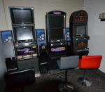 Trzy automaty do gier hazardowych i stojące przed nimi krzesła 
