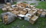 kilkanaście pudełek kartonowych i worek foliowy z suszem tytoniowym na podwórku na prywatnej posesji