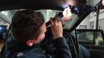 Na zdjęciu funkcjonariusz kontrolujący wnętrze samochodu za pomocą latarki.
