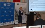 Dr Ilona Skibińska-Fabrowska, dyrektor lubelskiego oddziału NBP mówi do mikrofonu podczas konferencji. W tle widać dwa rollupy z logo Wydziału Ekonomicznego UMCS i NBP