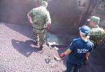 dwóch funkcjonariuszy Straży Granicznej i funkcjonariusz Służby Celno-Skarbowej w wagonie z rudą żelaza; przeszukują rudę; widoczny owinięty czarną folią pakunek