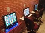 Trzy jednostki komputerowe ustawione na małych stolikach przy ścianie. Na monitorach kolorowe obrazki. Przy dwóch stolikach stoją obrotowe krzesła.