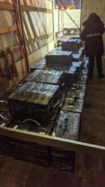 We wnętrzu naczepy tira stoi funkcjonariusz Służby Celno-Skarbowej. Cała podłoga wyłożona jest owiniętymi czarną folia pakunkami.