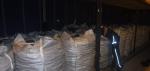 Kilkadziesiąt worków typu big bag stoi wzdłuż ściany naczepy. Do jednego z worków zagląda funkcjonariusz Służby Celno-Skarbowej. 