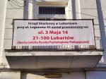 Balkon, na balustradzie wymieszony banner z informacją o nowym tymczasowym adresie siedziby Naczelnika Urzędu Skarbowego w Lubartowie.