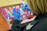 funkcjonariuszka służby celno-skarbowej w niebieskich gumowych rękawiczkach ogląda kolorowe plastikowe zabawki