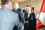 Funkcjonariuszka przyjmuje gratulacje od Dyrektora IAS.Z lewej strony stoi drugi funkcjonariusz. Z prawej fragm,ent sztandaru Izby Aministracji Skarbowej w Lublinie.