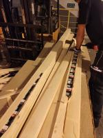 Funkcjonariusz stoi przy ułożonych deskach. Niektóre deski są rozłupane i widoczne są ułożone w nich paczki papierosów.