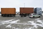 Samochód ciężarowy z dwiema przyczepami z kontenerami. Obok stoi radiowóz Służby Celno-Skarbowej 