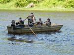 Uczniowie z instruktorem płyną łódką po rzece. 
