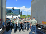 uczniowie klasy celno-skarbowej i funkcjonariusz Służby Celno-Skarbowej stoją przy ciężarówkach na przejściu granicznym