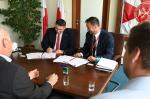 Dyrektor IAS Lublin i jego zastępca podpisują dokumenty przy biurku.