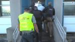 Policjanci i funkcjonariusz Służby Celno-Skarbowej prowadzą podejrzanego po schodach do budynku