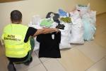 Funkcjonariusz Służby Celno-Skarbowej kuca przy workach z ubraniami 