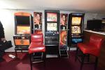 Trzy automaty do gier hazardowych stoją obok siebie. Przed nimi dwa czerwone krzesła