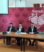 3 osoby siedzą przy biurku.