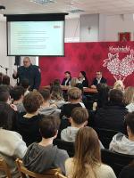 Mężczyzna prowadzi szkolenie, sala pełna ludzi.