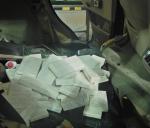 Zdemontowana tylna kanapa samochodu, na niej leży owinięte w biały materiał kilkadziesiąt paczek papierosów 