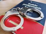 zdjęcie kodeksu postępowania karnego; na kodeksie ułożone kajdanki