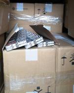 Poustawiane jedno na drugim kartonowe pudła. Na jednym z nich paczki z papierosami.